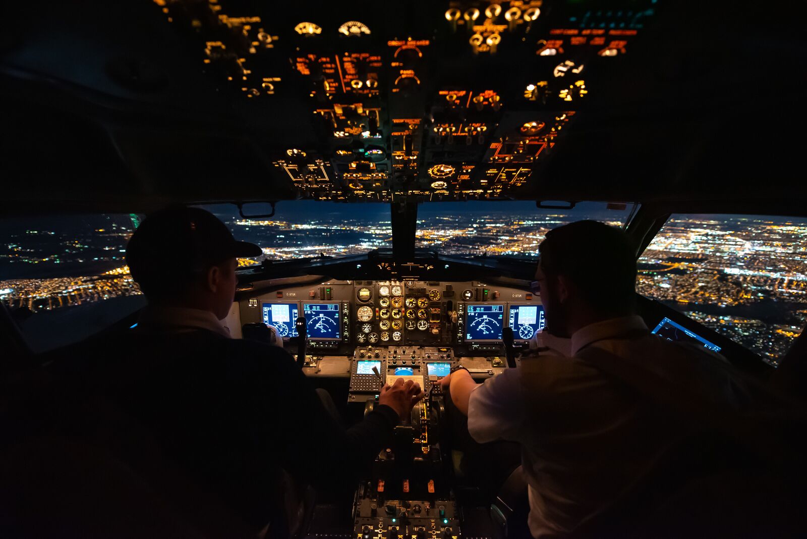 Two pilots in a lit cockpit at night